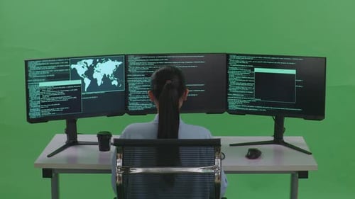 Asiatische Entwicklerin verwendet Computer, um Code mit mehreren Bildschirmen auf grünem Bildschirm zu schreiben