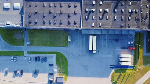 Aerial shot of industrial warehouse. Loading hub and many trucks with cargo trailers. Aerial view of