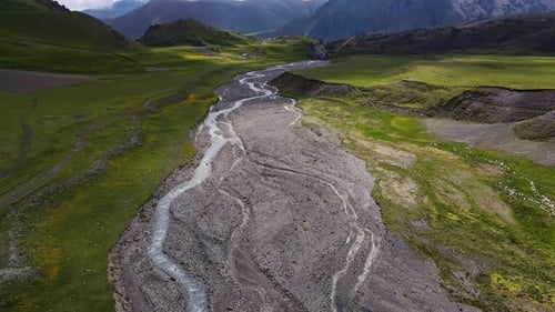 Aerial View of a Mountain River Valley Among Green Meadows