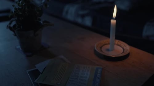 Hand putting house key on little table in living room lit by candle. Static