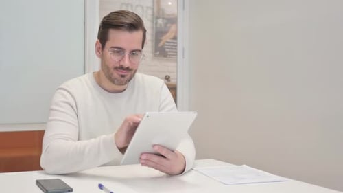 Middle Aged Man Celebrating Success on Tablet in Office