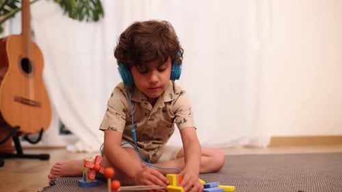 Boy Wearing Headphones Plays with Toys on Floor