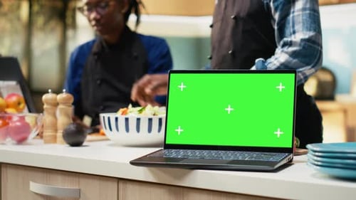 Chroma Key Screen on Laptop Next to Lovers Preparing a Meal at Home