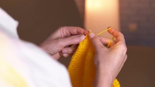 Hands Knitting Yellow Yarn with Knitting Needles