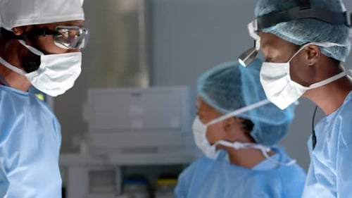 Diverse surgeons wearing surgical gowns operating on patient in operating theatre, slow motion