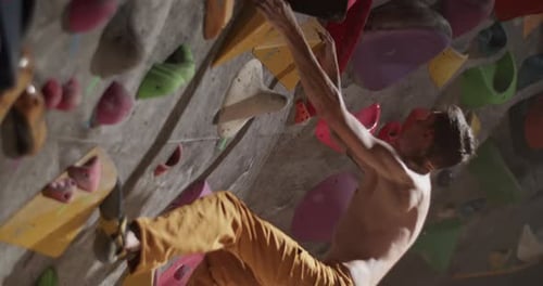 Male Rock Climber Training at Climbing Wall in Gym