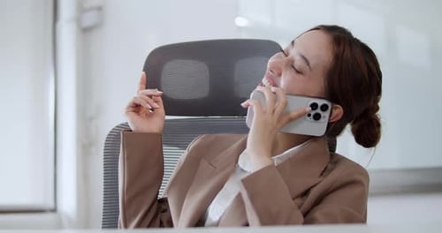 Eine Geschäftsfrau genießt ein lebhaftes Telefongespräch in ihrem modernen Büro und präsentiert eine positive Arbeit