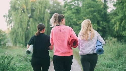 Women Walking with Yoga Mats in Nature
