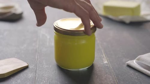 Male;s hand opens ghee butter pot