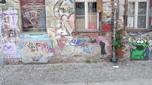 Weitwinkelaufnahme der Grafitti Street Wall, auf einem verlassenen Gebäude neben einem Kopfsteinpflasterweg, auf einem