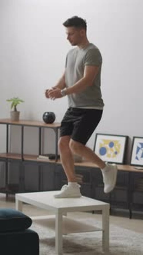 Young Man Exercising Indoors Using Coffee Table