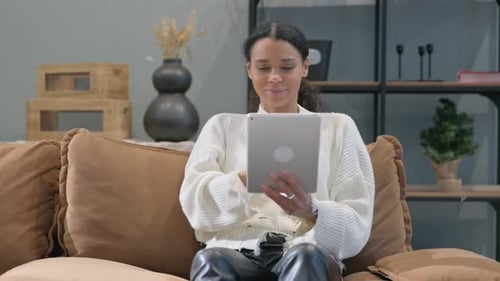 Woman Using Tablet Sitting on Couch Indoors