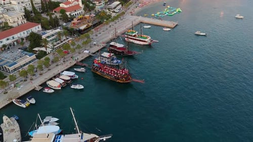 Boats docked at a scenic waterfront with a view of Saranda, Albania, during a peaceful sunset