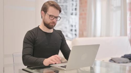 Focused Man Typing on Laptop at Desk