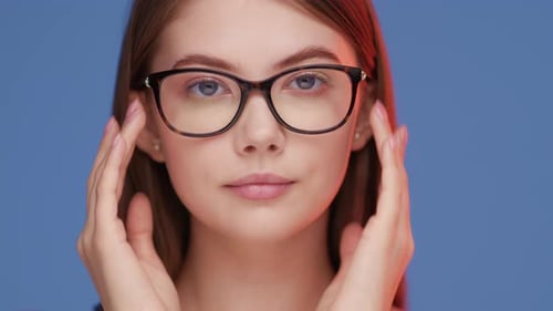Young Woman Puts on Glasses Studio Portrait