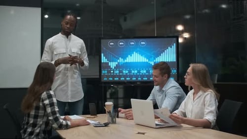 Two male programmers and two female system administrator stand over the workplace, look at computer