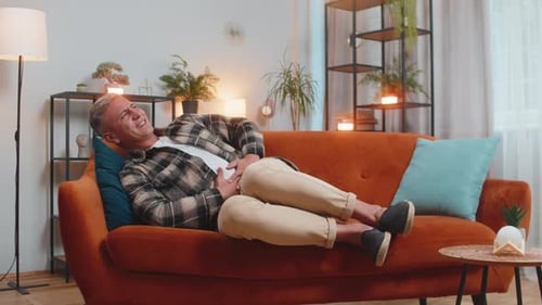 Man on Couch Holding Stomach in Discomfort