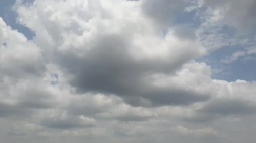 Blue summer sky with very dense thick rain clouds moving across the heavens. Fast cloud formation an