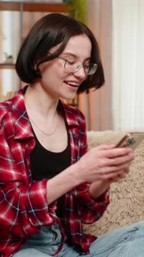 Enthusiastic Young Woman Using Phone on Sofa