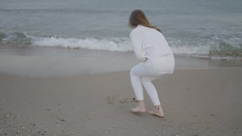 Rückansicht einer nicht wiederzuerkennenden Frau schreibt Wort in den Sand