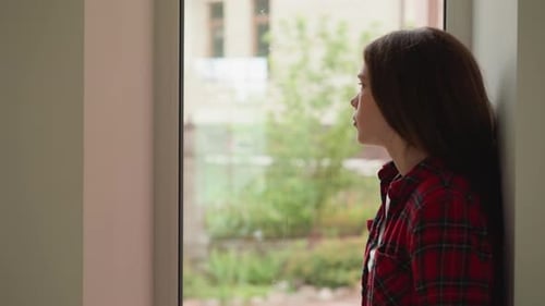 Woman Looking Out Window Wearing Plaid Shirt
