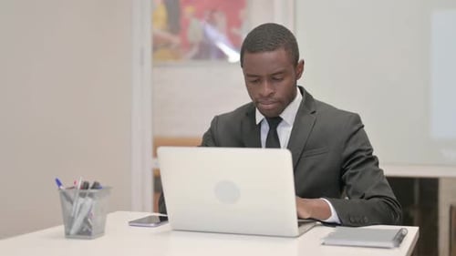 African Businessman Working on Laptop while Sitting in Office