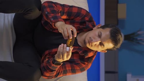 Young Adult Taking Pills from Bottle at Home