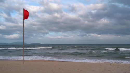 Beach with a red flag waving in wind