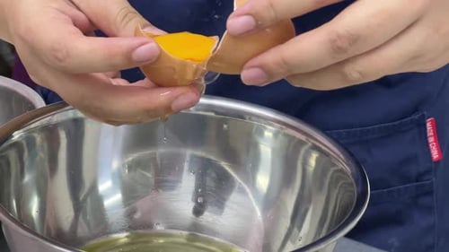 Chef separating egg yolk into bowl, close up