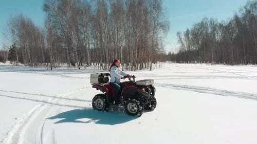 Woman Driving ATV on the Snow Field Man Rides Behind