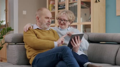 Mature Couple Relaxing with Tablet on Sofa