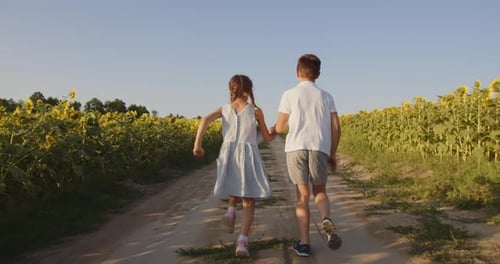 Little Boy And Girl Are Running Across The Field