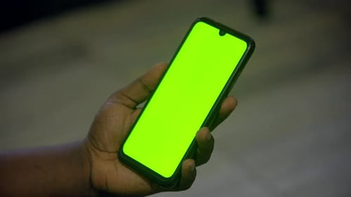 mobile green screen in man hand unlocks and play video in portrait mode.