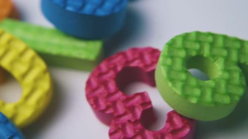 Motion Past Pile of Foam Rubber Numbers on White Surface