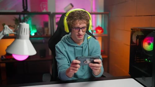 Young Adult Gamer Playing Mobile Game at Desk