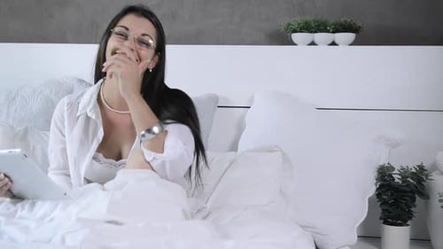 Smiling Woman Using Tablet in Bed