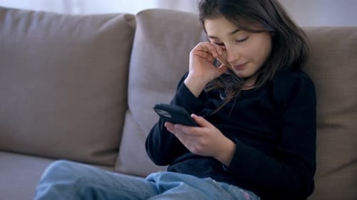 Upset Girl Using Phone on Couch