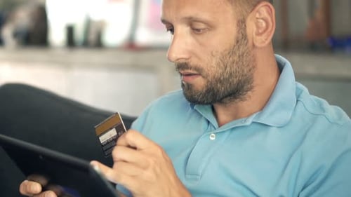 Man using tablet and credit card at home