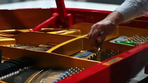 Close up of a man fixing a red piano