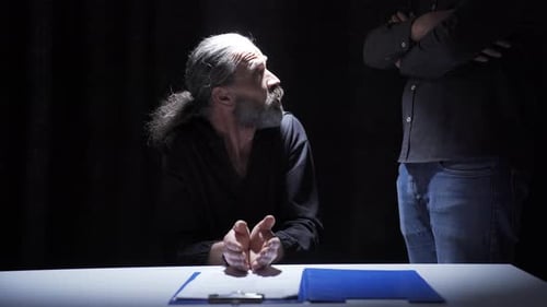 The suspected criminal is being questioned in the interrogation room by the authorized police office