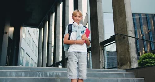 Smiling Boy Standing Outside School Building Holding Book