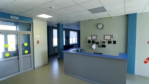 Reception Desk Sits in Building Lobby Near Entrance Doors