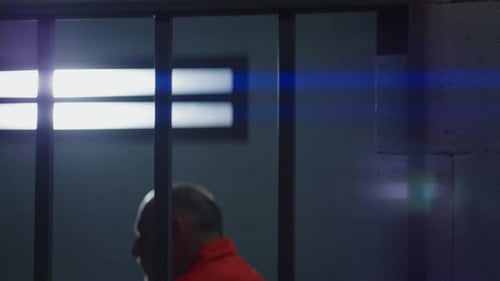 Man in Orange Jumpsuit Behind Prison Bars