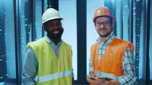 Two Engineers Wearing Safety Gear Work Together at a Contemporary Industrial Facility
