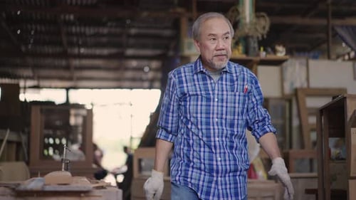 Asian senior carpenter walking and wearing protective eyewear preparing for working at the carpentry