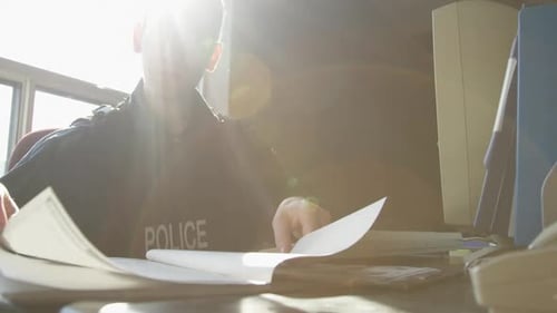 Police Officer Reviews Paperwork in Bright Office