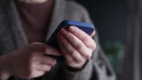 Close-up view on female hands with mobile phone at home, using messenger