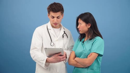 Doctor and Nurse Consult Tablet on Blue Background