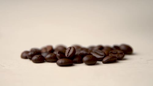 Coffee Beans Falling on to Pale Surface