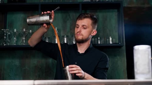 Young Bartender Pouring Cocktail in Urban Bar Setting